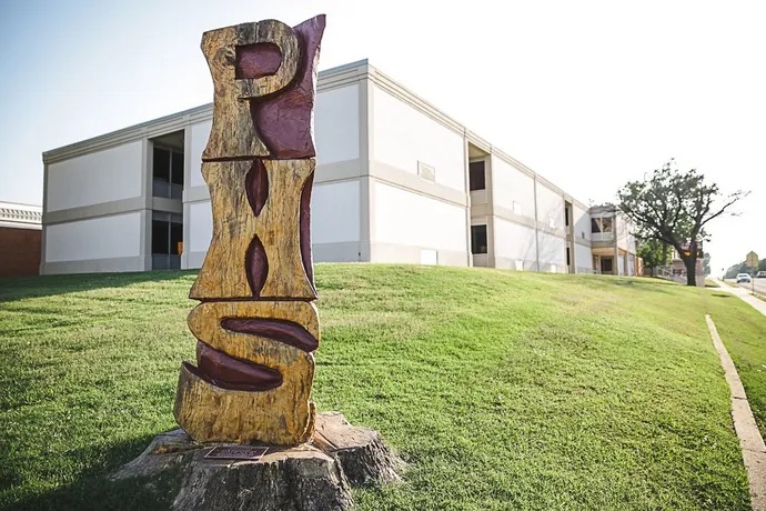Logo sculture of PHS and a white building behind it
