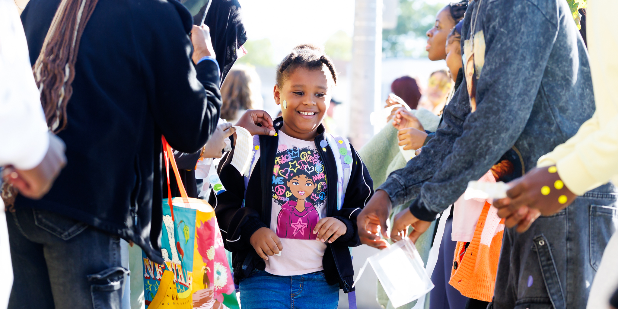 A student smiles while walking through a crowd of people.