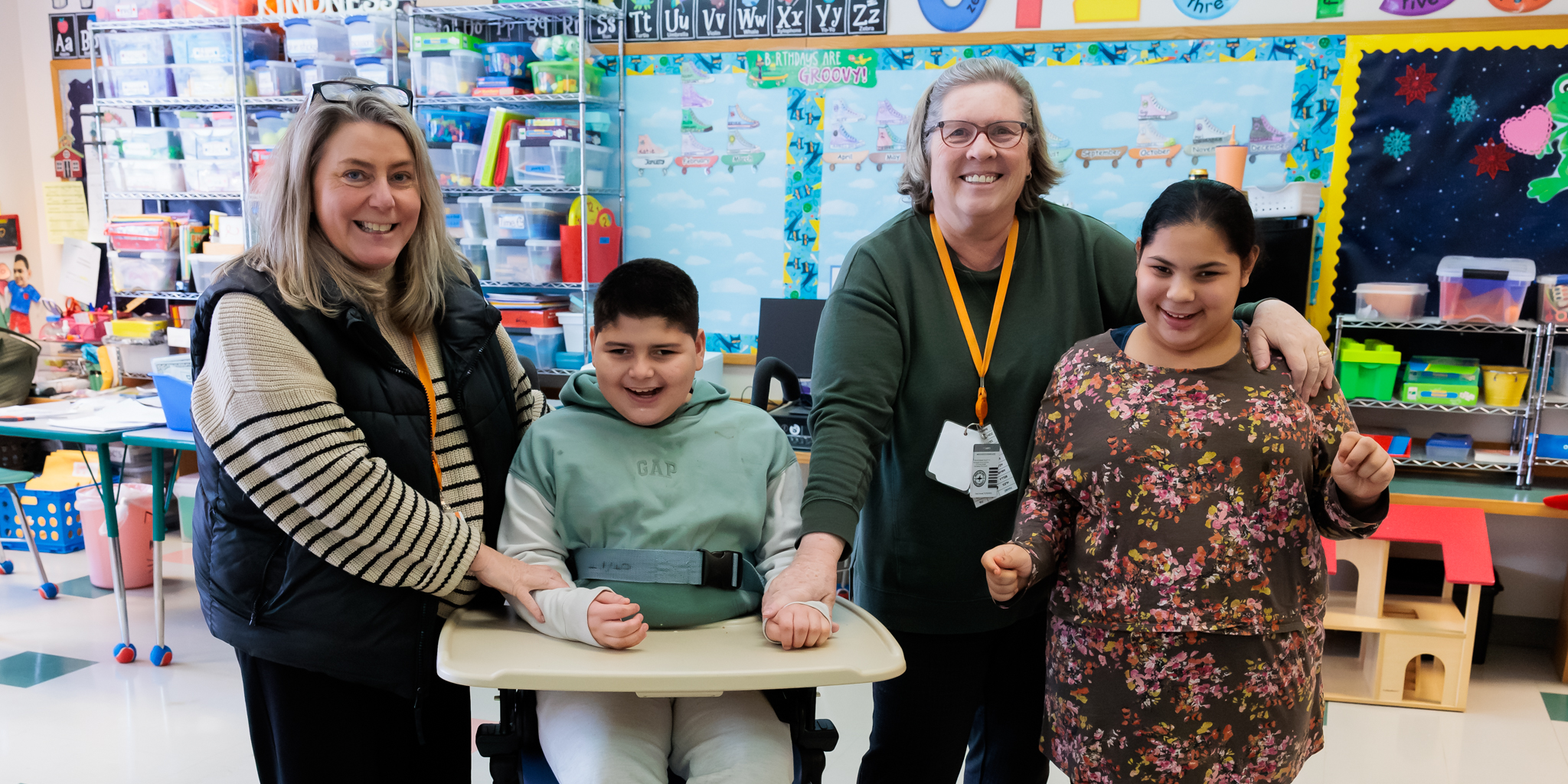 Two staff members stand with two students together.