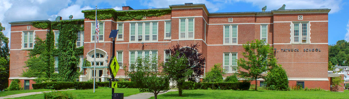 Tatnuck Elementary red brick two story building full of windows with green ivy growing up the side and along the roof