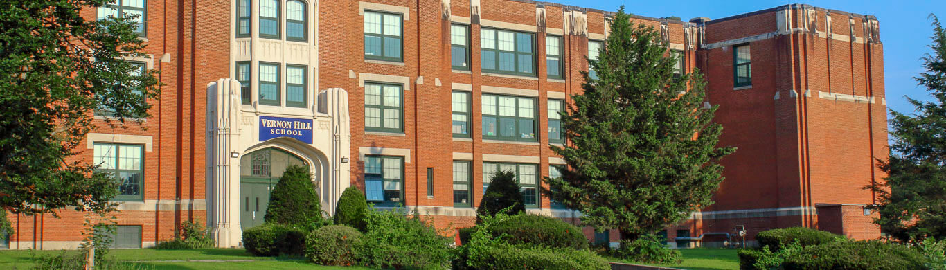 Vernon Hill Elementary view from outside the front door seeing the landscaped lawn and tall brick building 