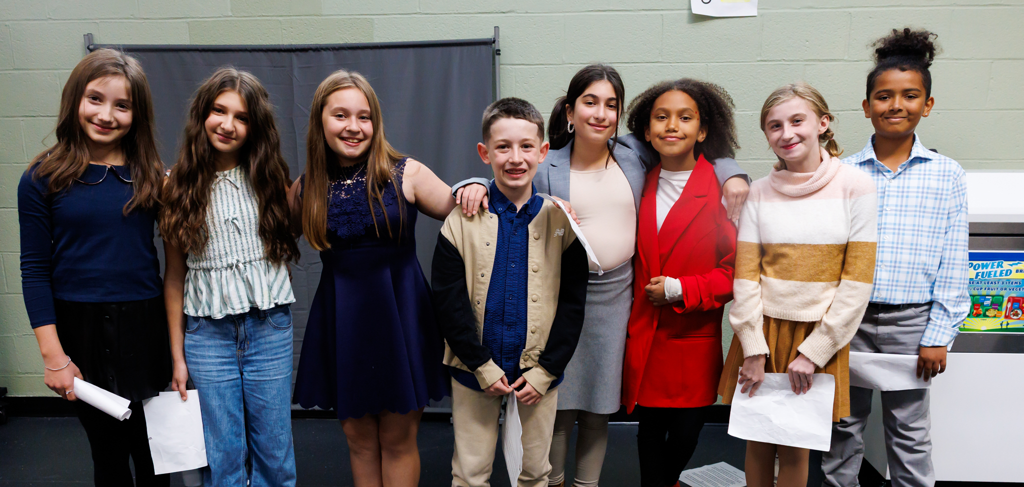 Students stand together and smile.