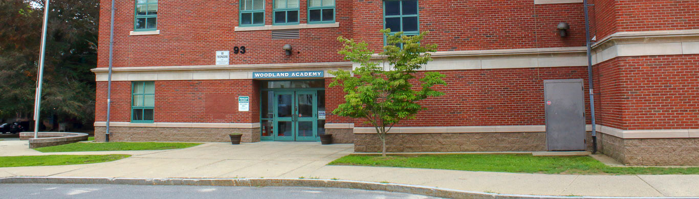 Woodland academy view of green door entrance from the street to the tall red brick and green windowed building.