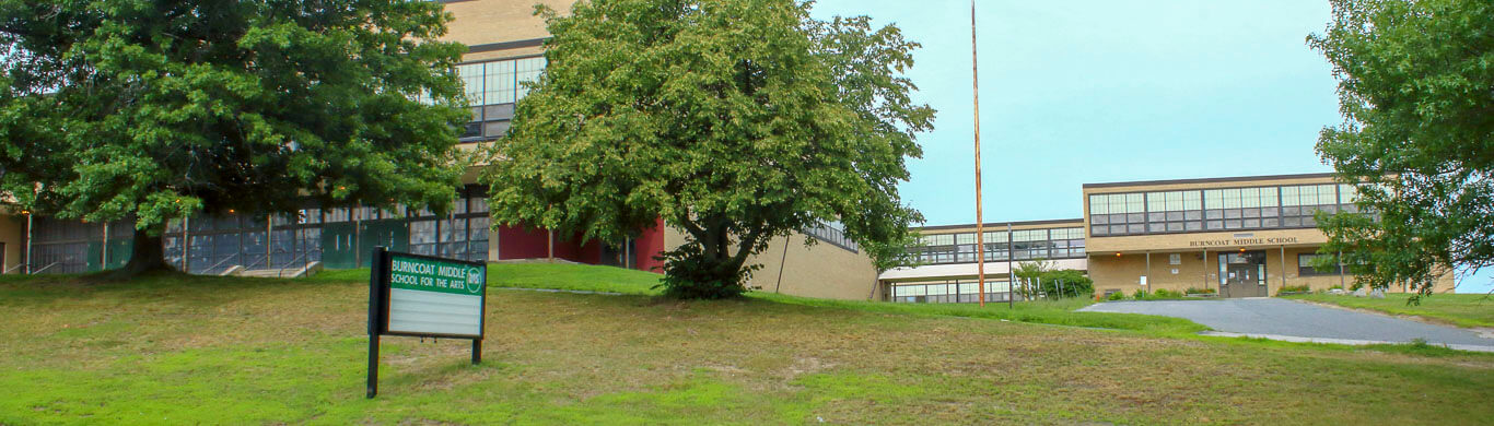 Burncoat Middle view from the street of a driveway entrance into a circular campus of tan buildings 