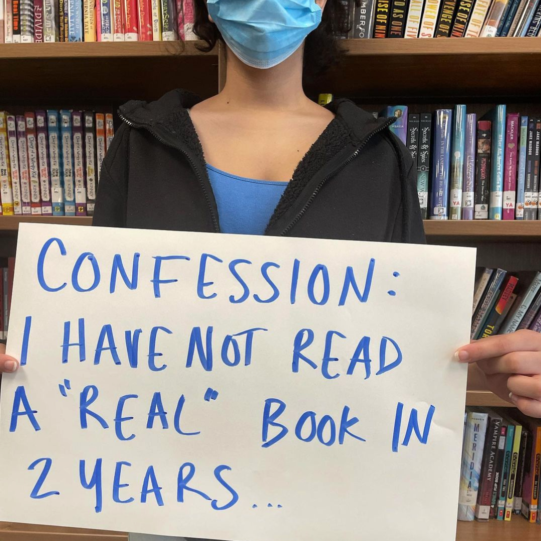 Photo of a student holding a sign that says, "I have not read a real book in 2 years."