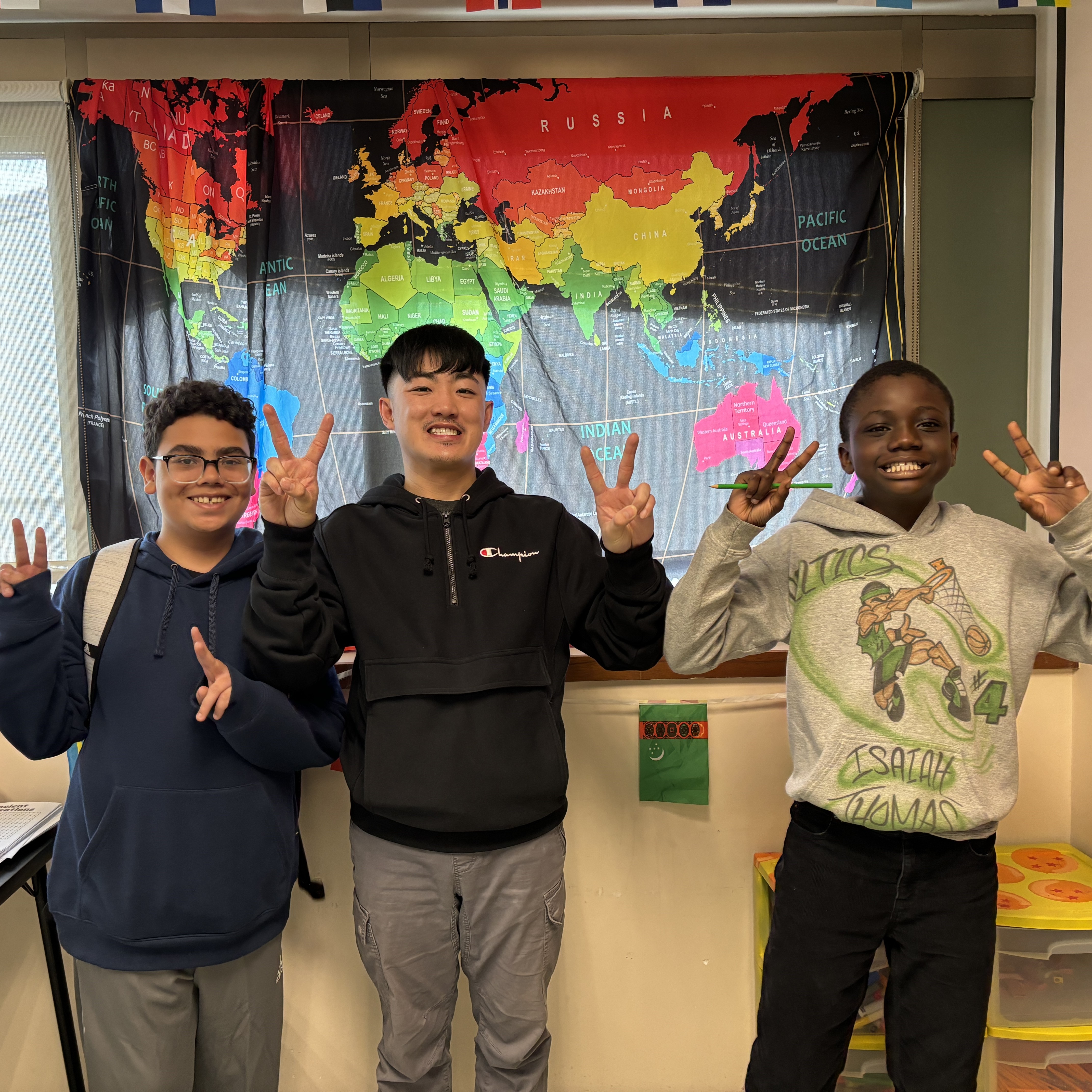Forest Grove Middle School teacher posing and smiling with two students in a lively classroom setting.