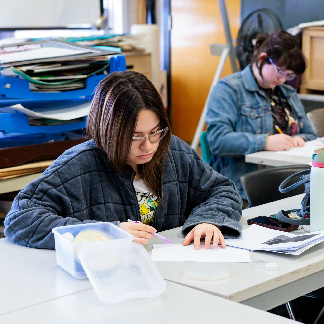 A student focuses on art work.