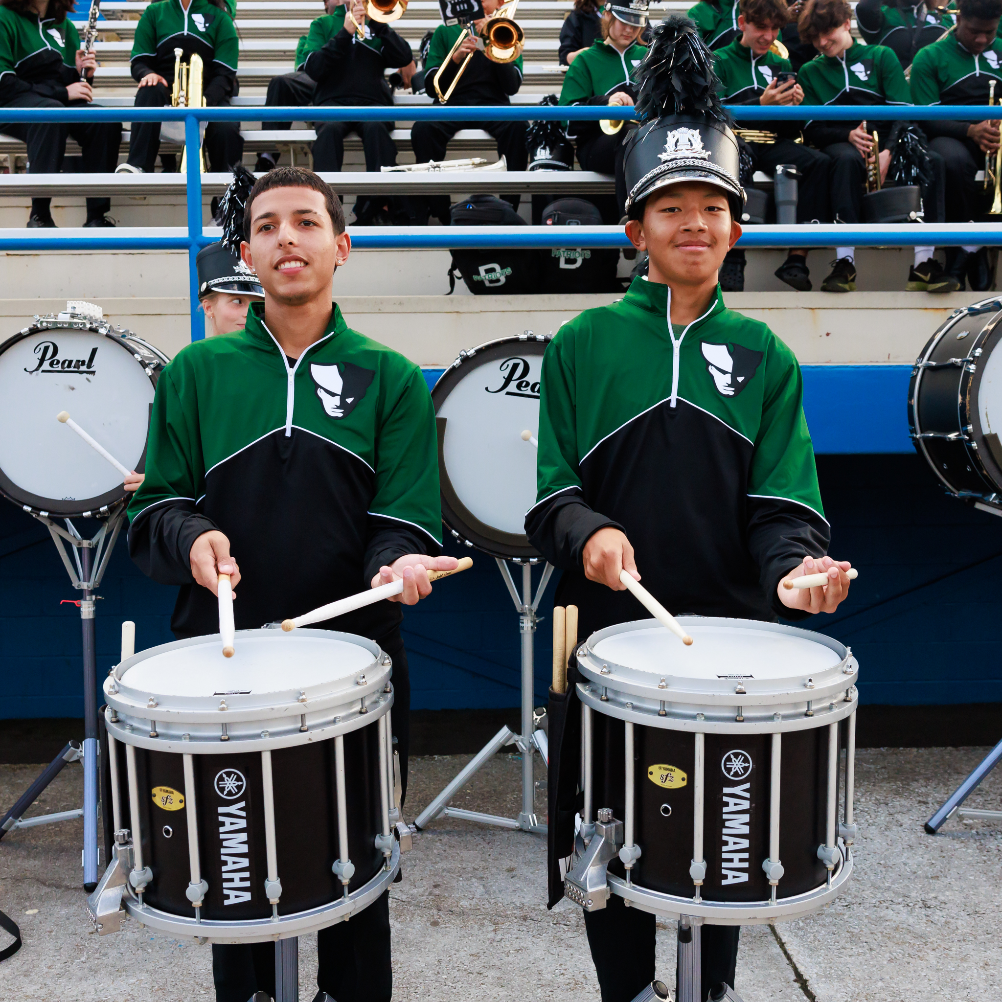 Two drummers perform during a football game.