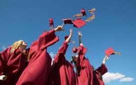 Students throwing their graduation caps in the air wearing red gowns