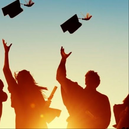 Two students silhouettes throwing their graduation caps in the air