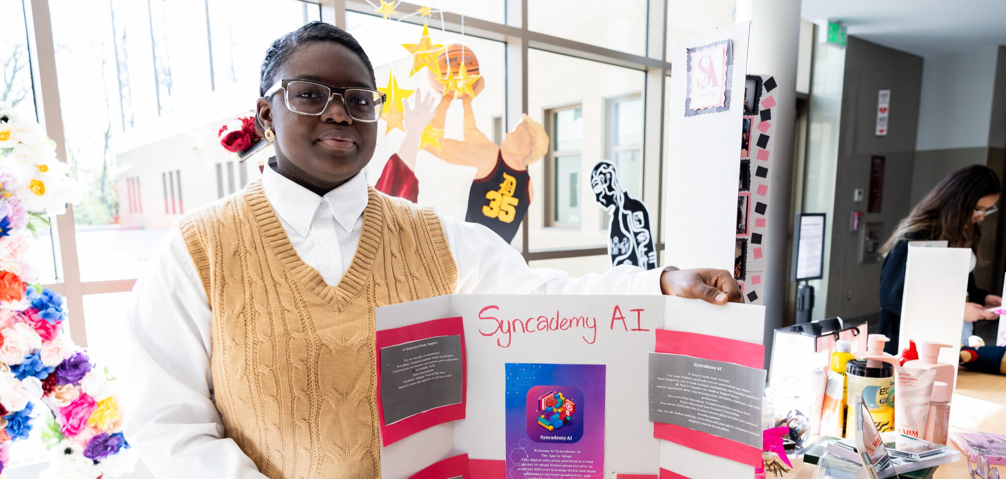 A student stands beside their project during a recent business fair.