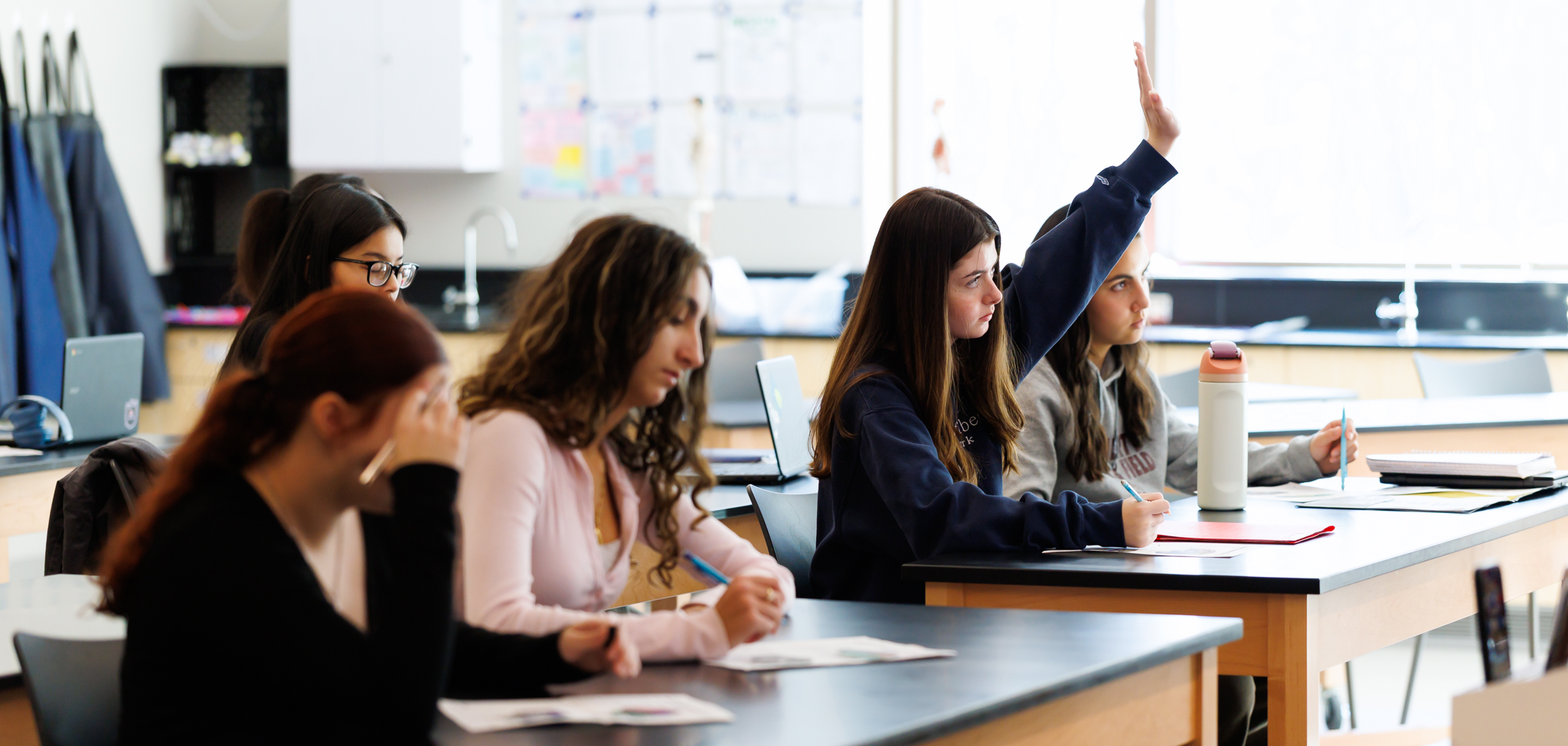 A student raises their hand to answer a question during class.
