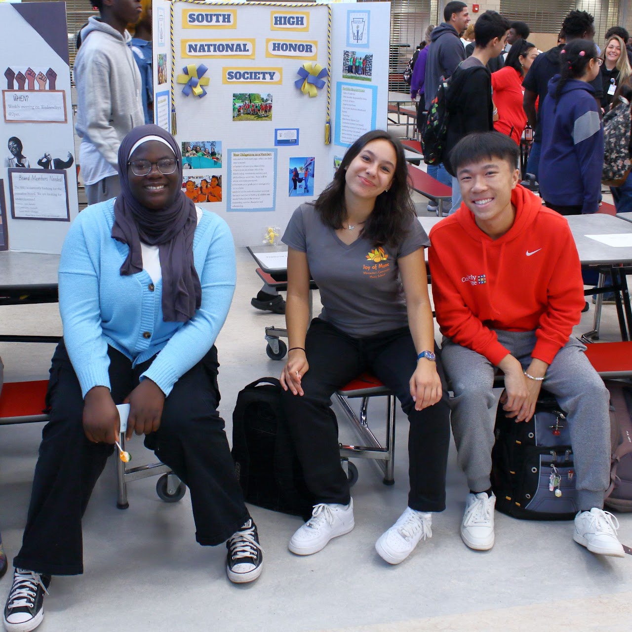 Three students smiling in a school cafeteria