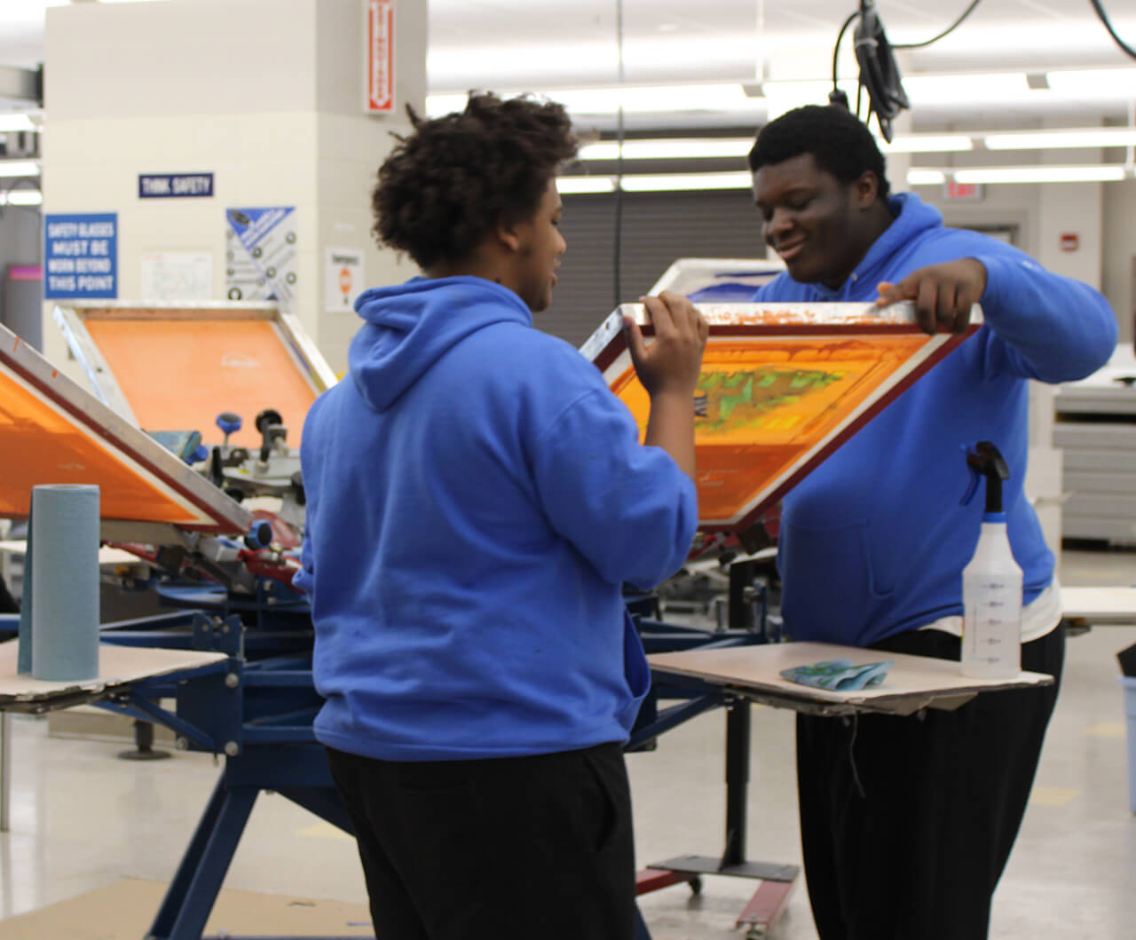 two students printing a canvas