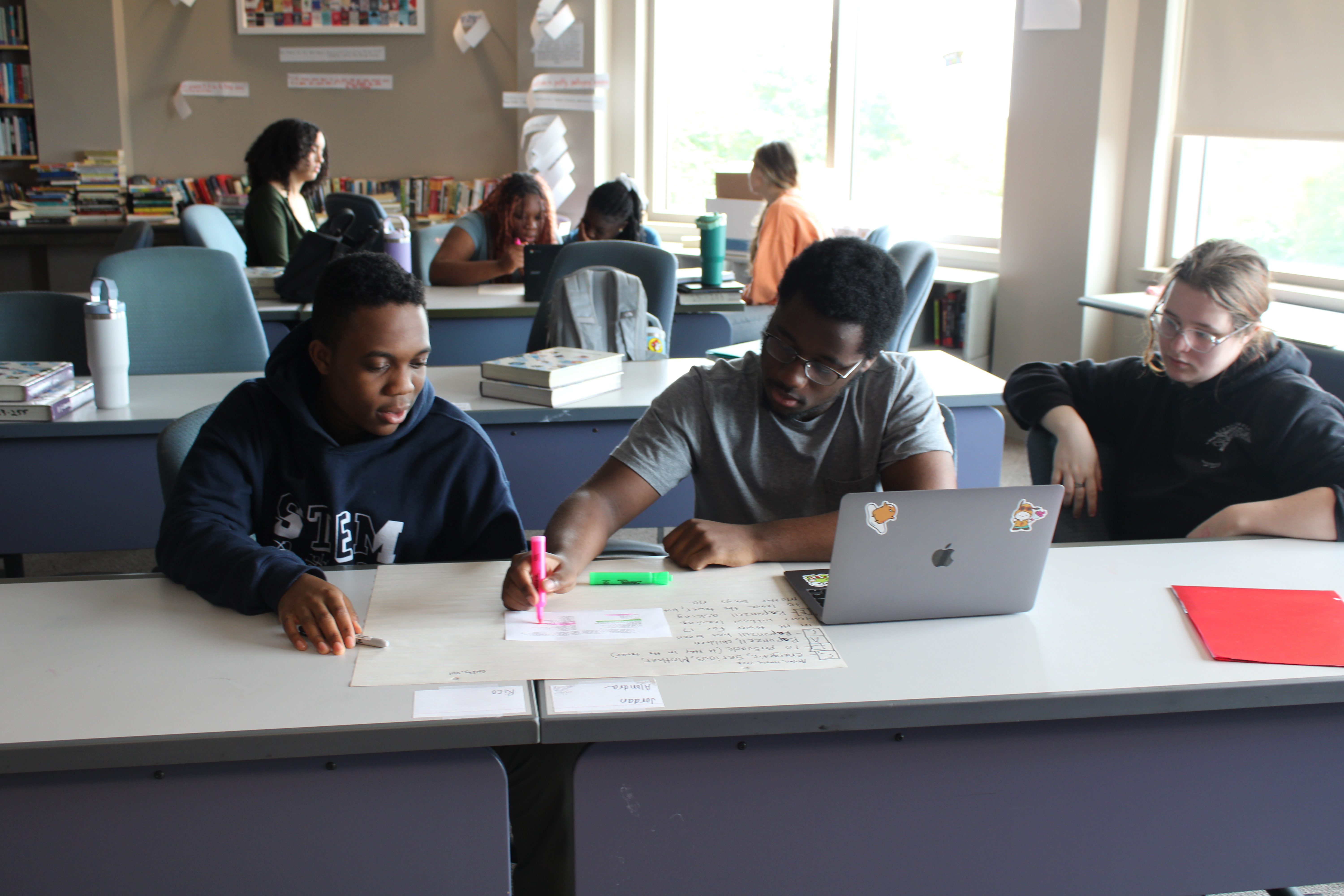 3 students writing and highlighting on paper 