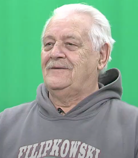 Man in grey sweatshirt in front of a green screen.