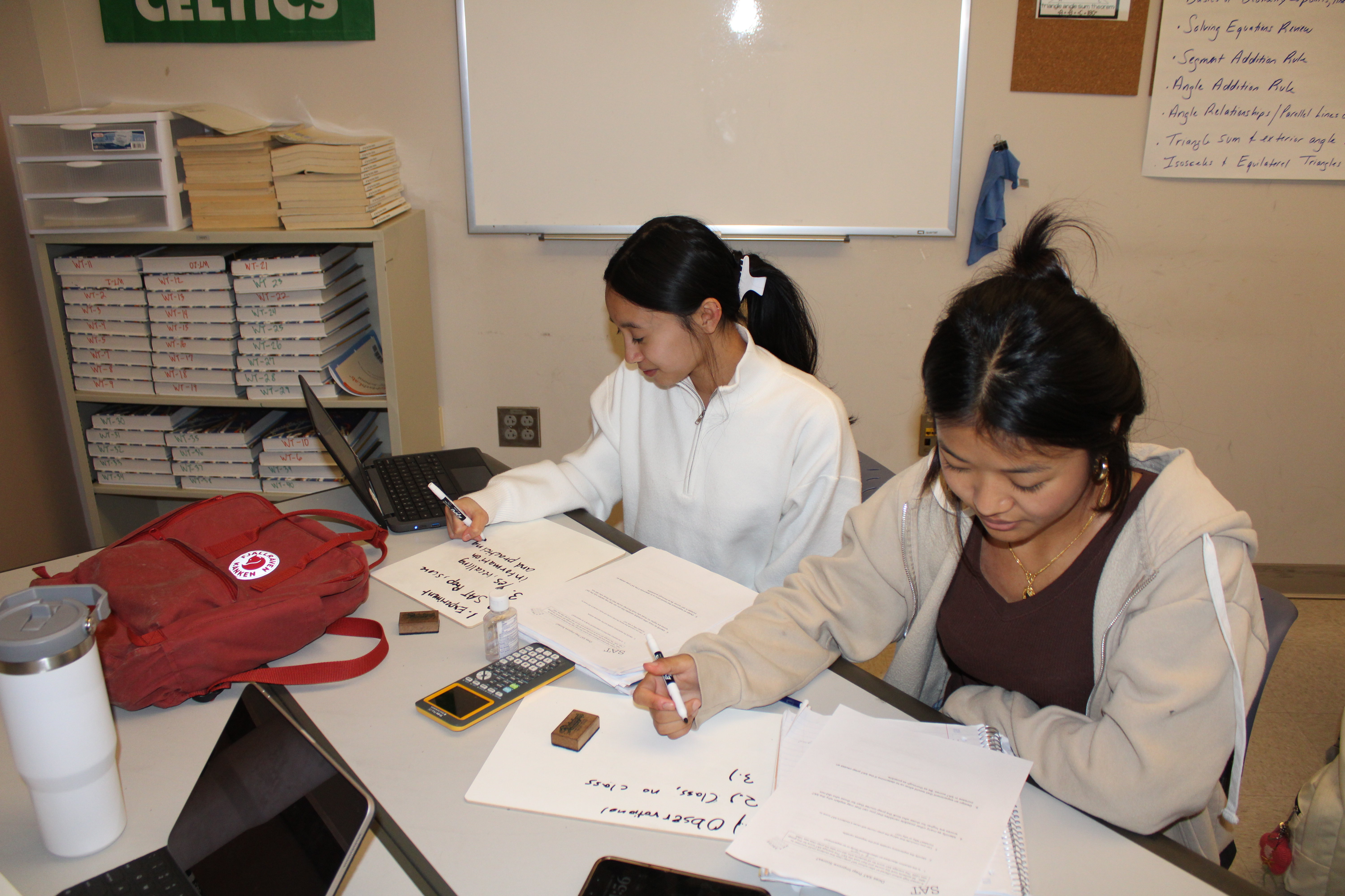 Two girls working independently in math class on whiteboards. 