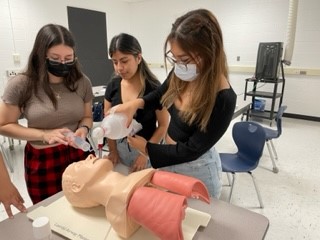 Three three girl students learning  CPR 