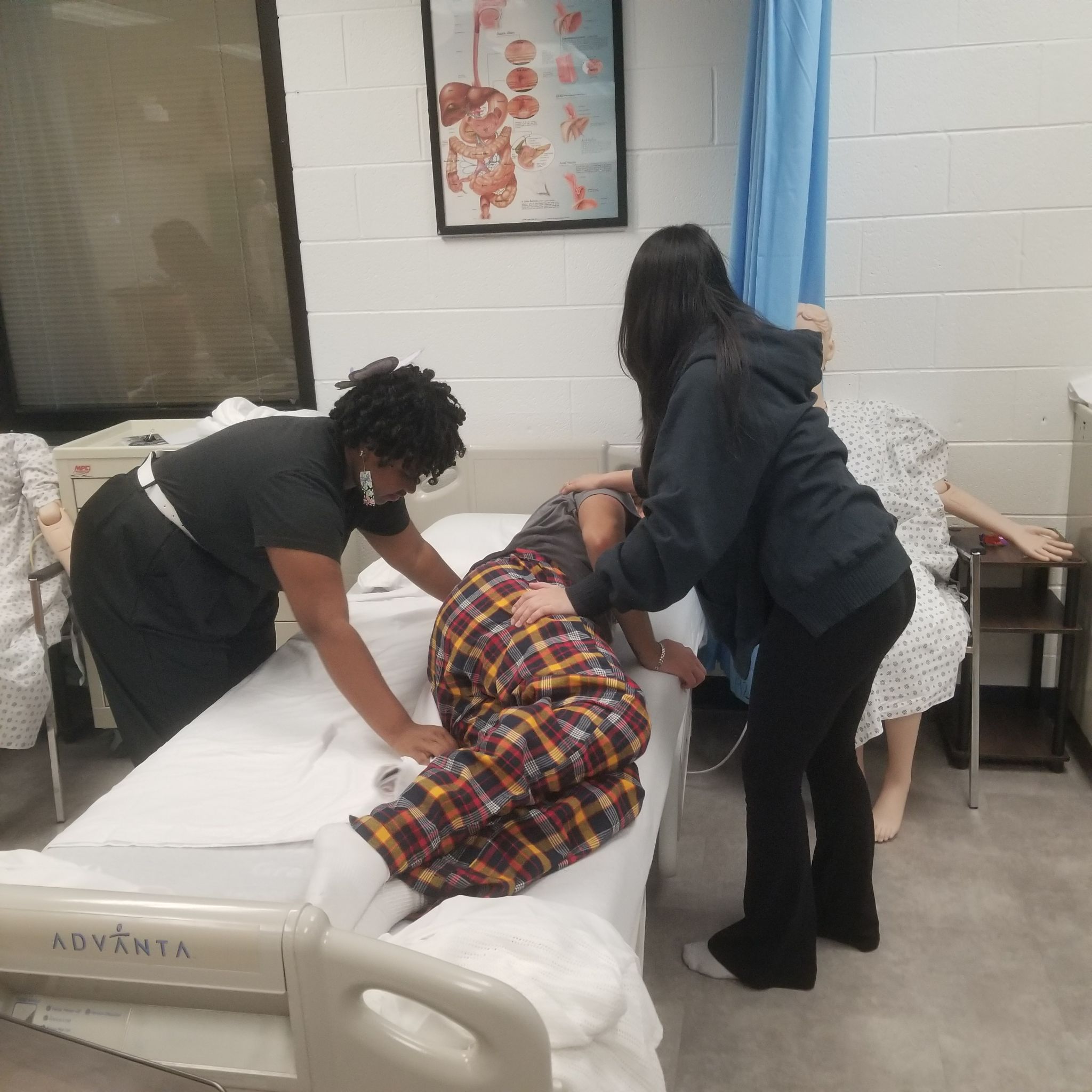 Two students helping one to lay down in bed