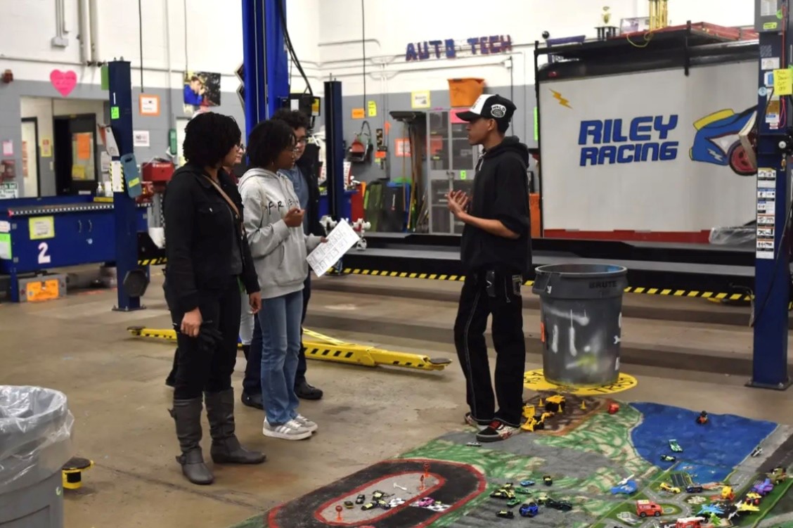 Students teaching other students how to change oil. 