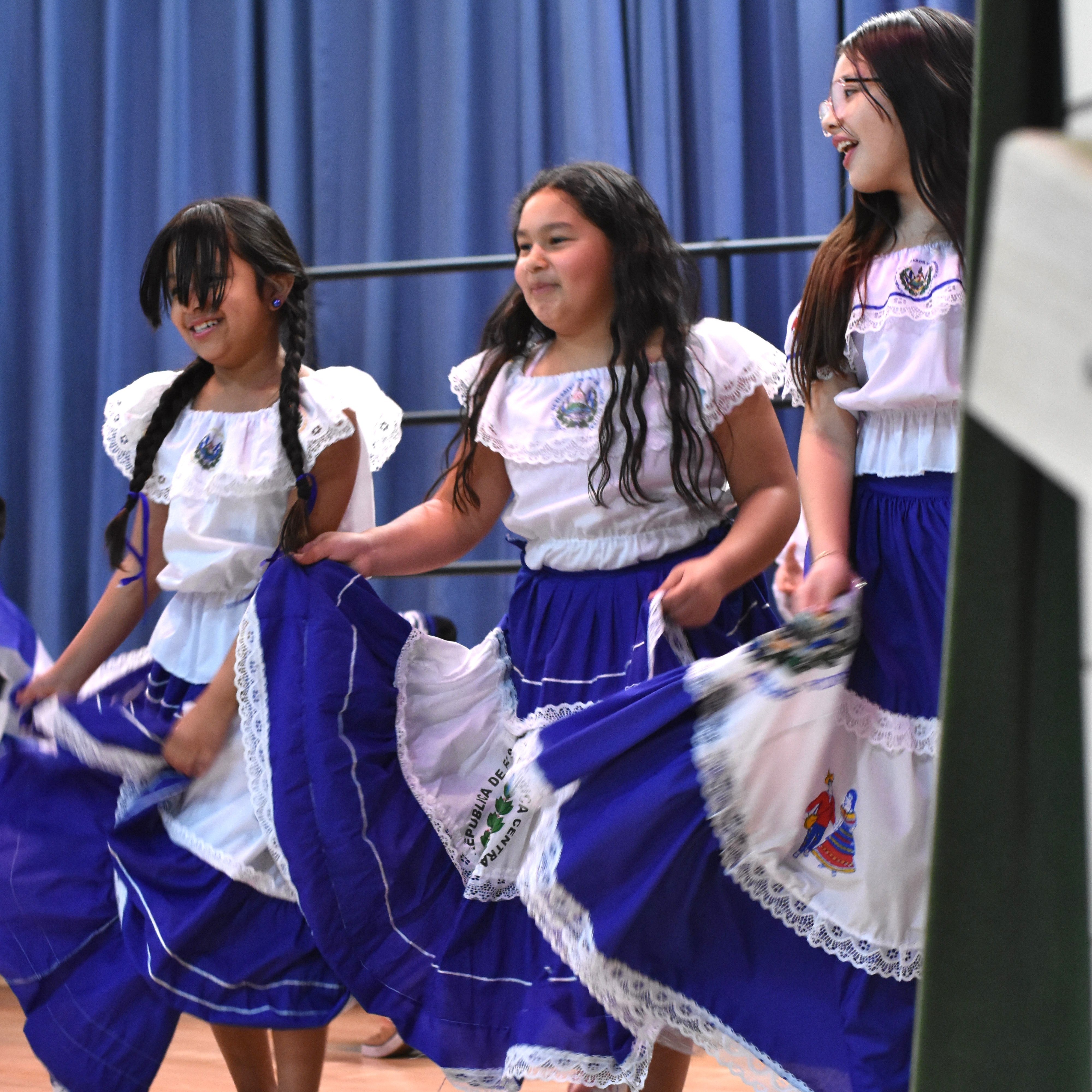 Three smiling students dancing in dresses at Dean International Night