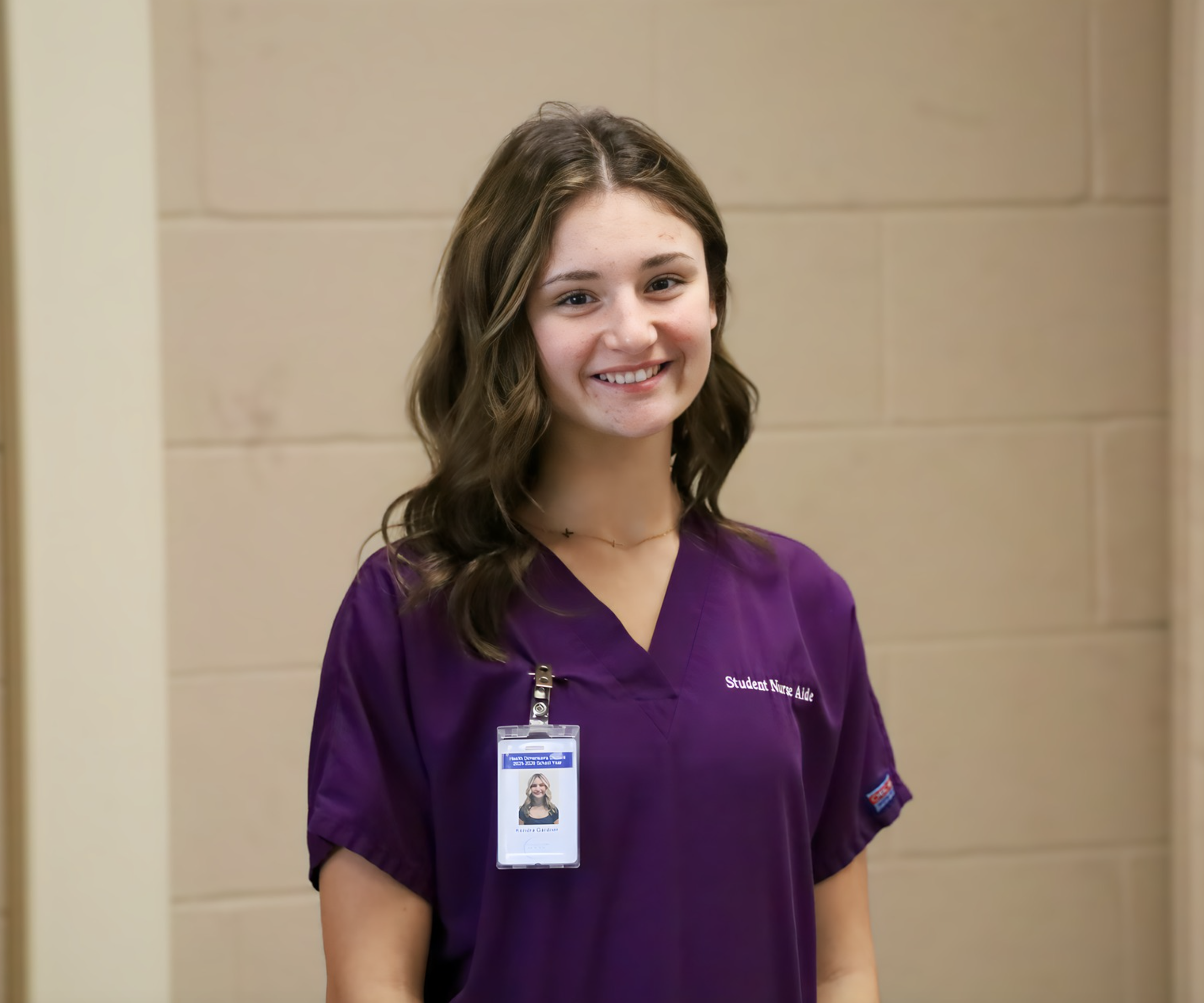 Kendra wering scrubs and her badge in her classroom.  