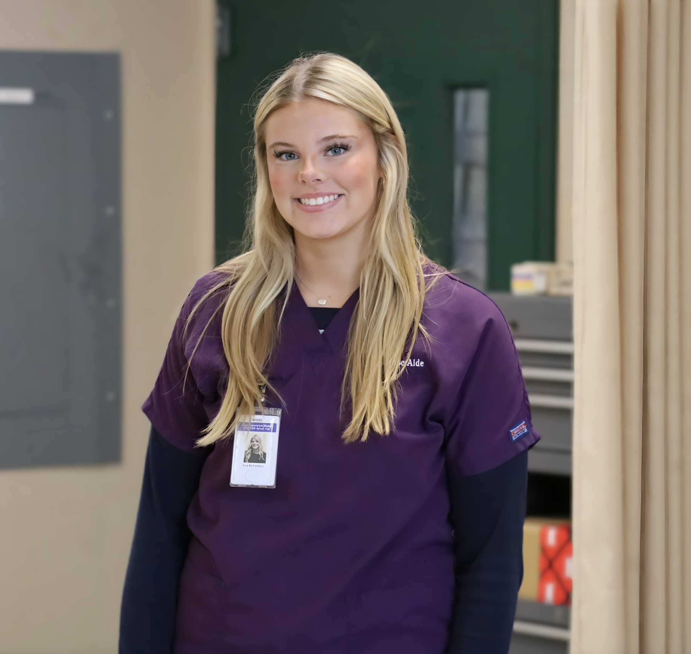 Ava smiling for the camera wearing her scrubs in her classroom.  