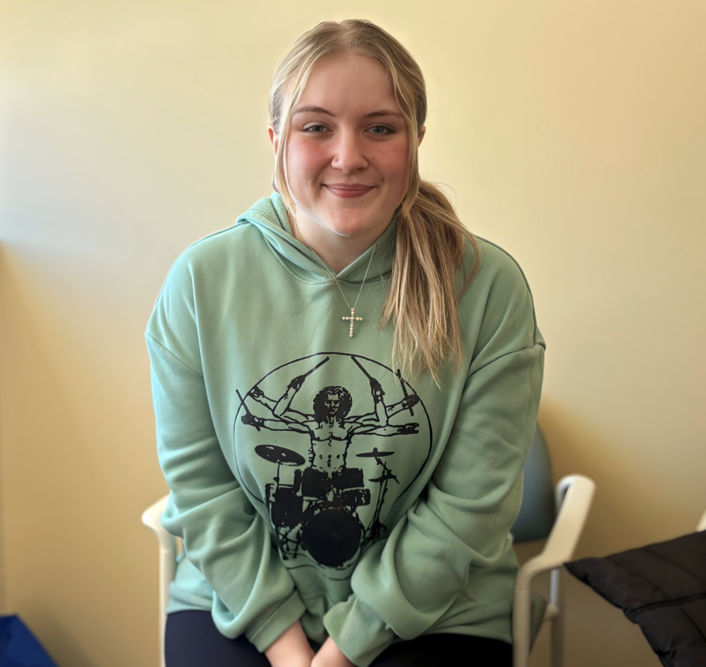 Jaidyn sitting in a chair smiling for the camera in between classes.