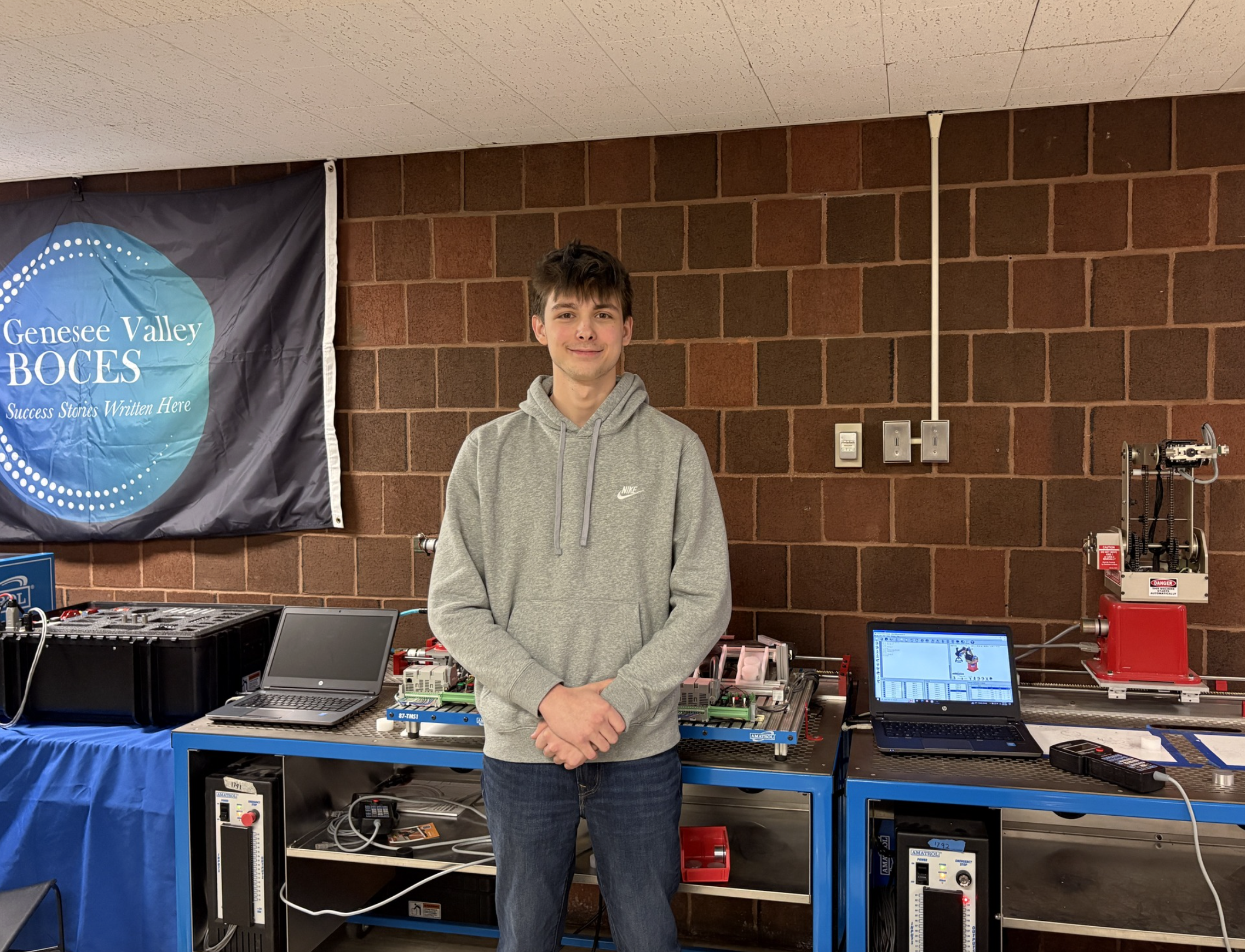 Brennen is standing in front of a table with his robots in the background.