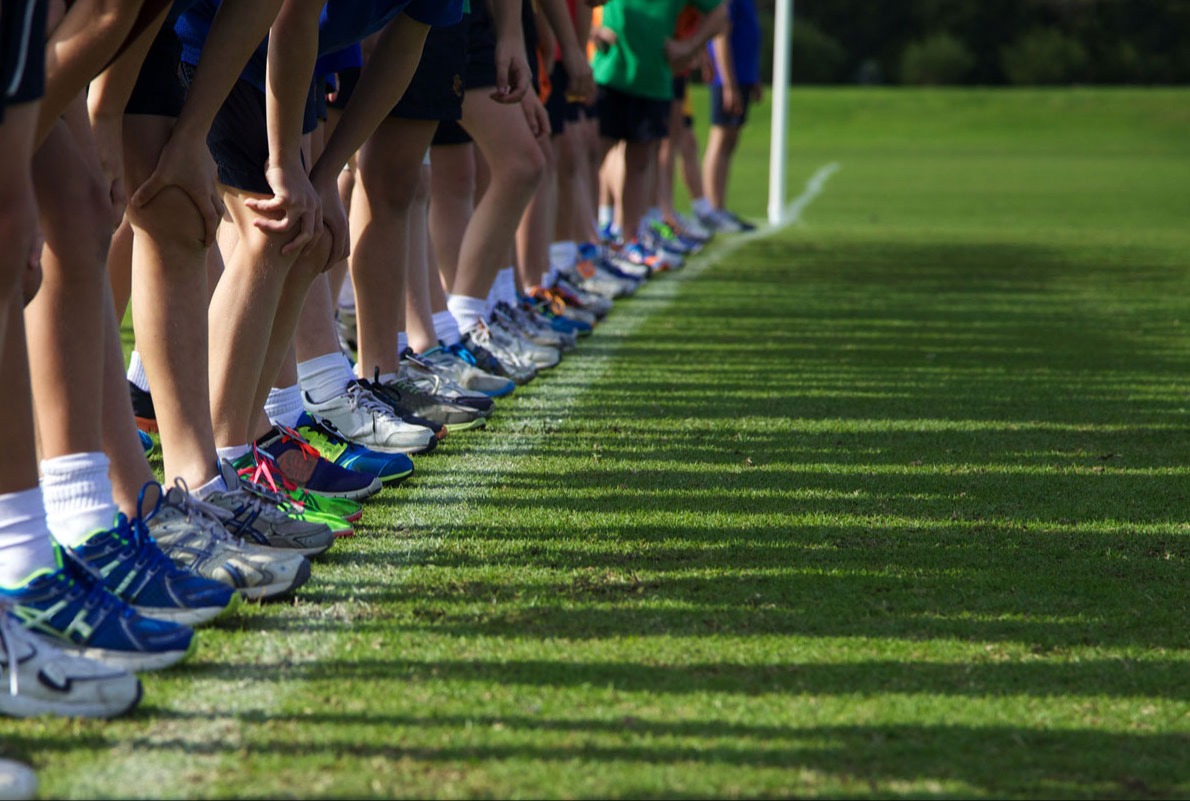 people standing on a line with many different color shoes. They are bending over as if about to start a race.