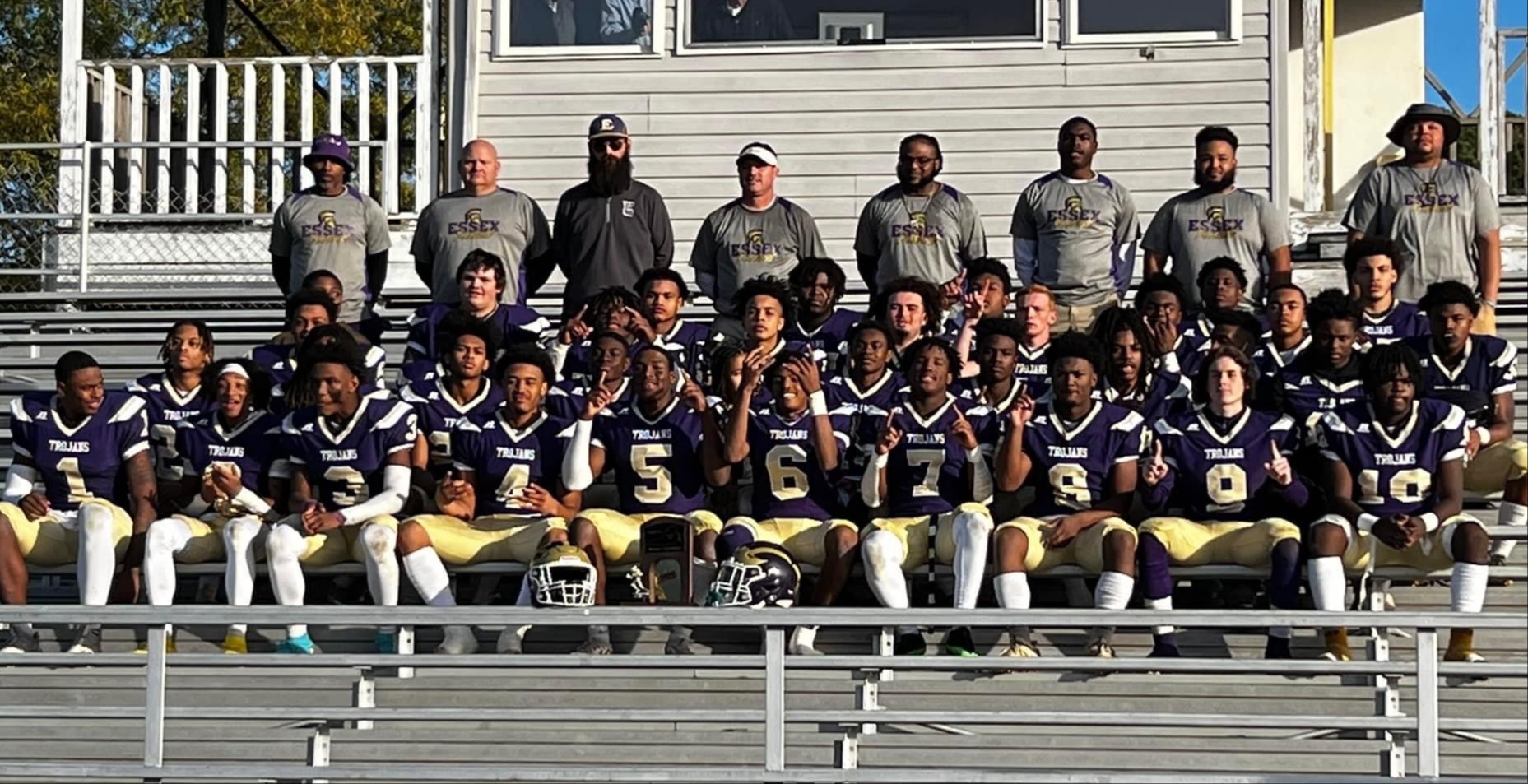 Essex Football team sitting on bleachers with coaches standing behind in the background.