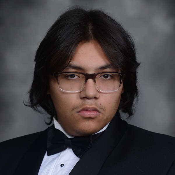 Senior Portrait of Evan Miles. He is wearing a white shirt with a black jacket and a black bow tie. He is wearing brown and clear framed glasses.The portrait is just a headshot, form the chest up.