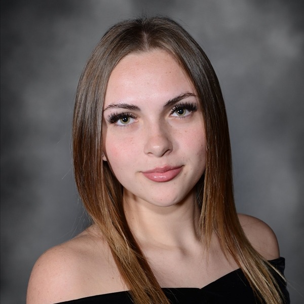 Senior Portrait of Sage Woods. She is wearing a black wrap slightly off the shoulders. Her light brown hair is straight and hanging on both sides. The portrait is just a headshot, form the chest up.