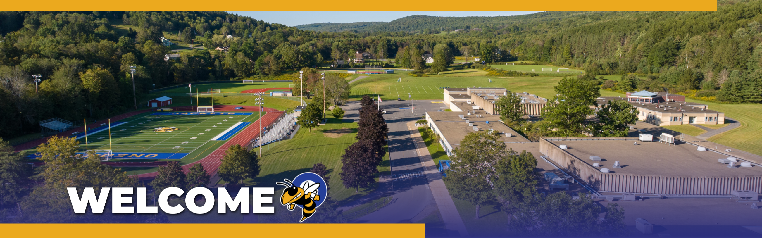 Aerial view of a school with a football field, parking lot, and lush greenery. Text reads "WELCOME".