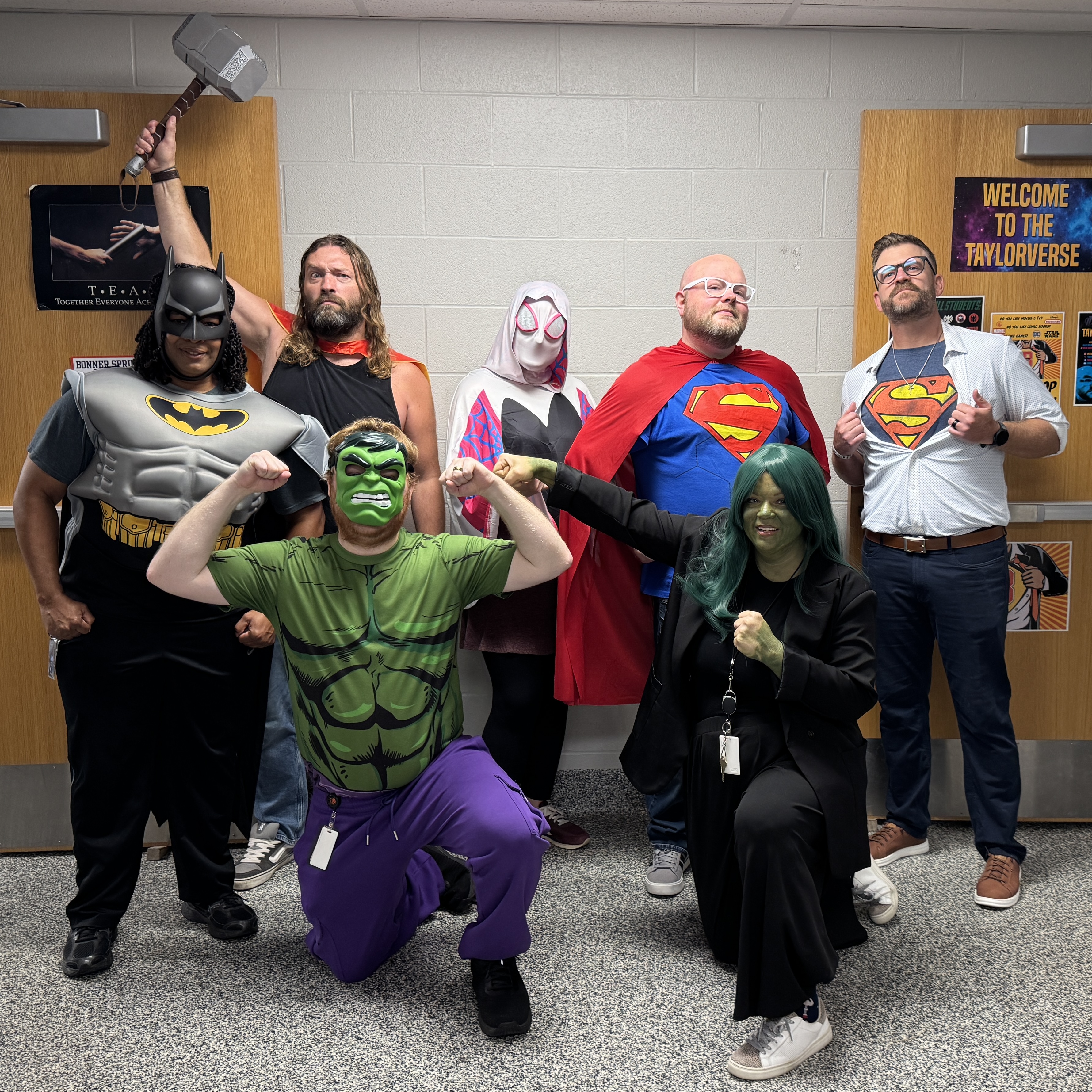 A group of people dressed in superhero costumes, posing for a photo with a backdrop.