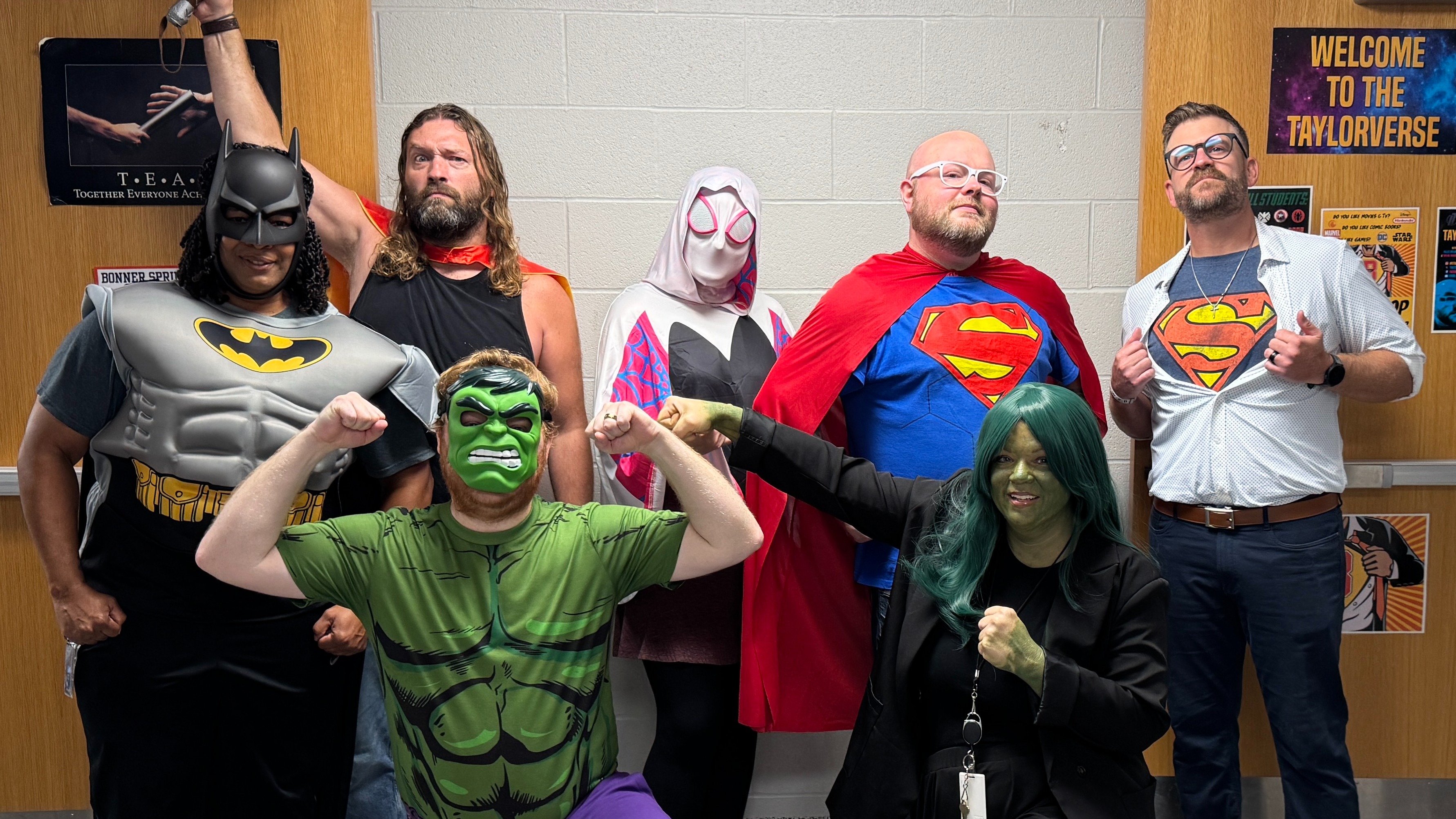 A group of people dressed in superhero costumes, posing for a photo with a backdrop.