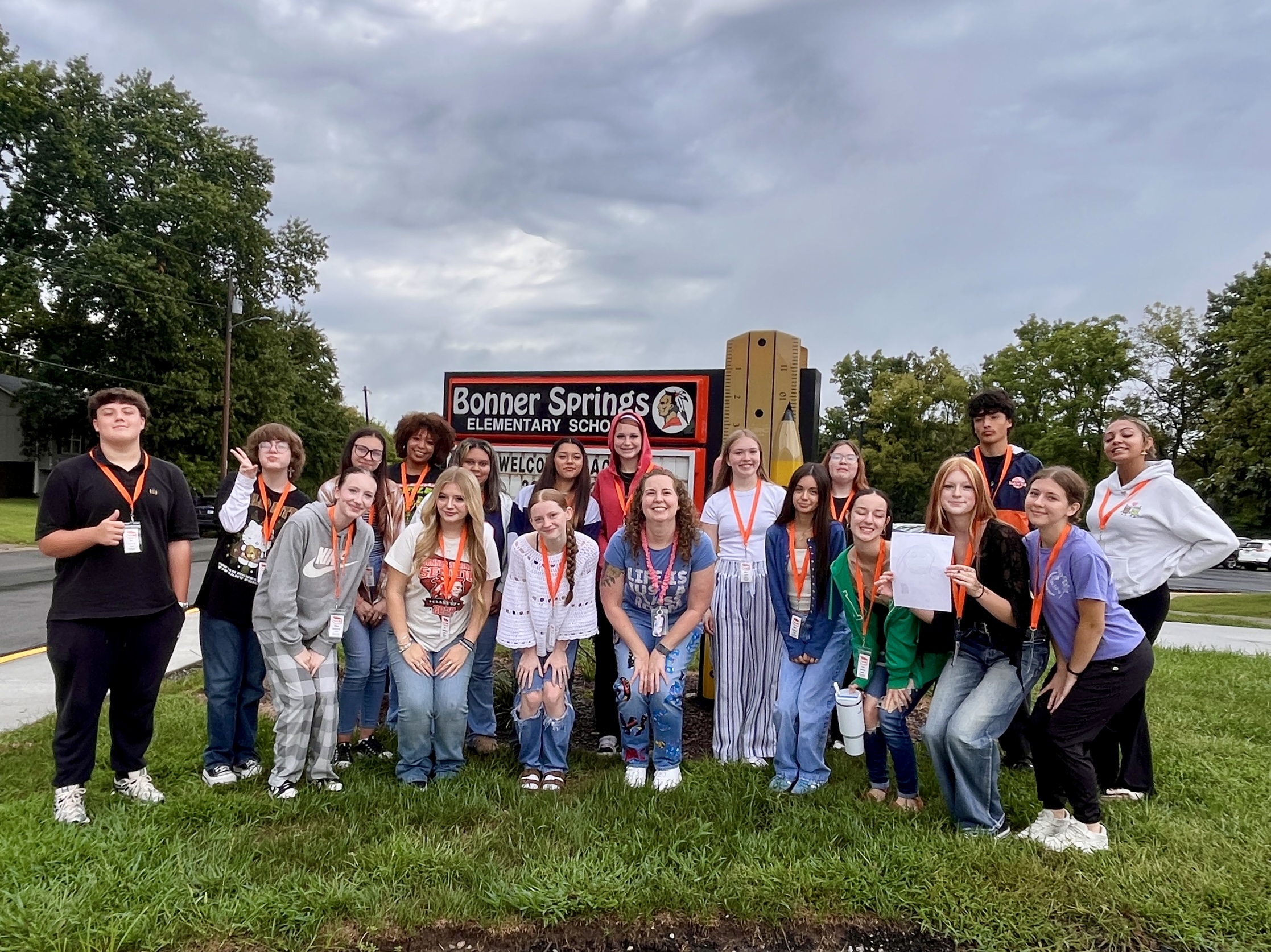 Group of young people wearing name tags posing for a photo in front of a sign.