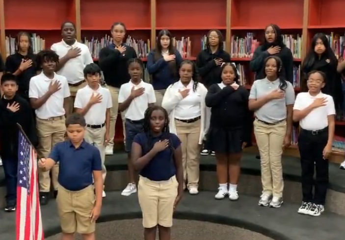 A class of student conducting the pledge.