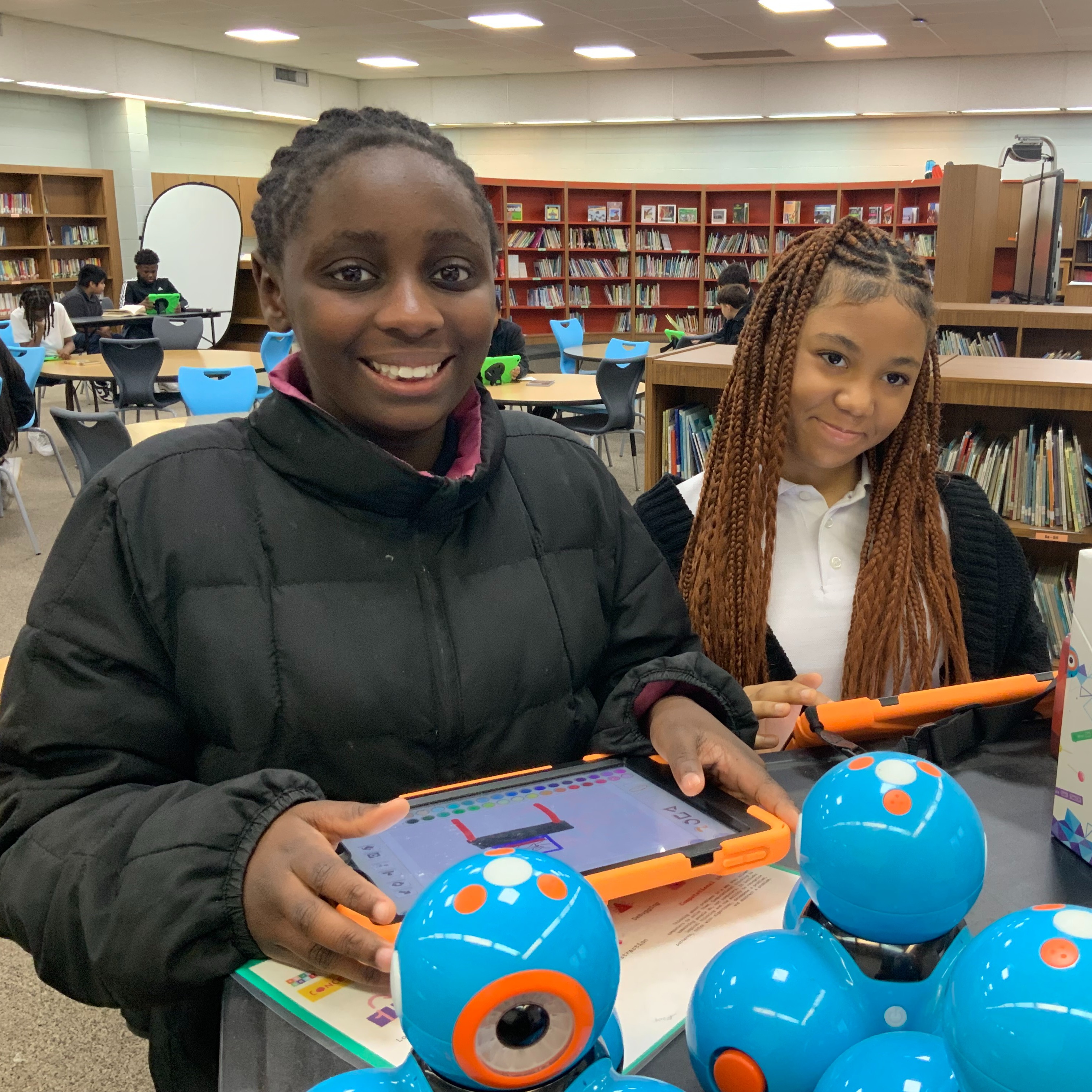Two girls working on iPads and Wonder Bots.