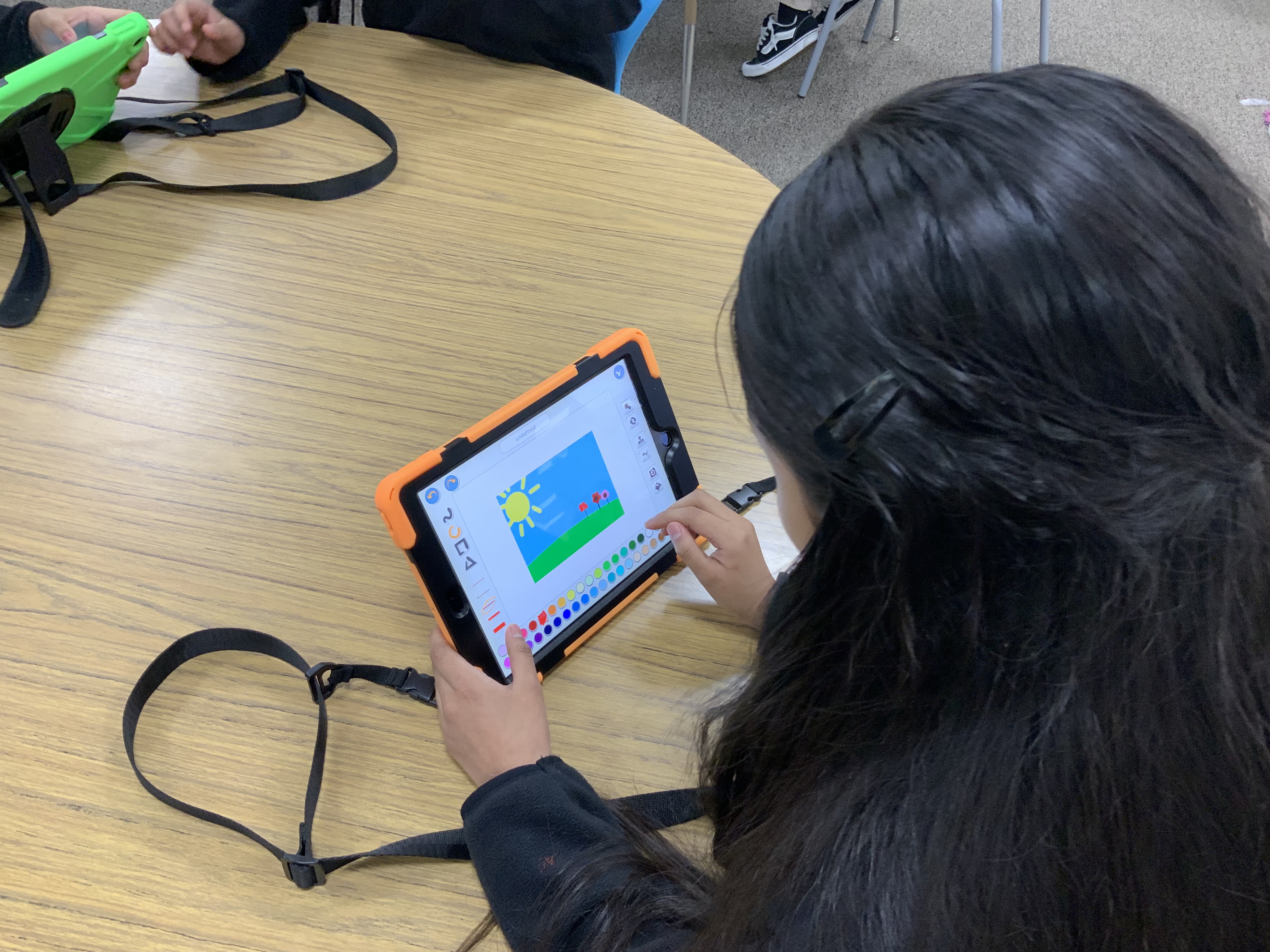 Student drawing on iPad at table