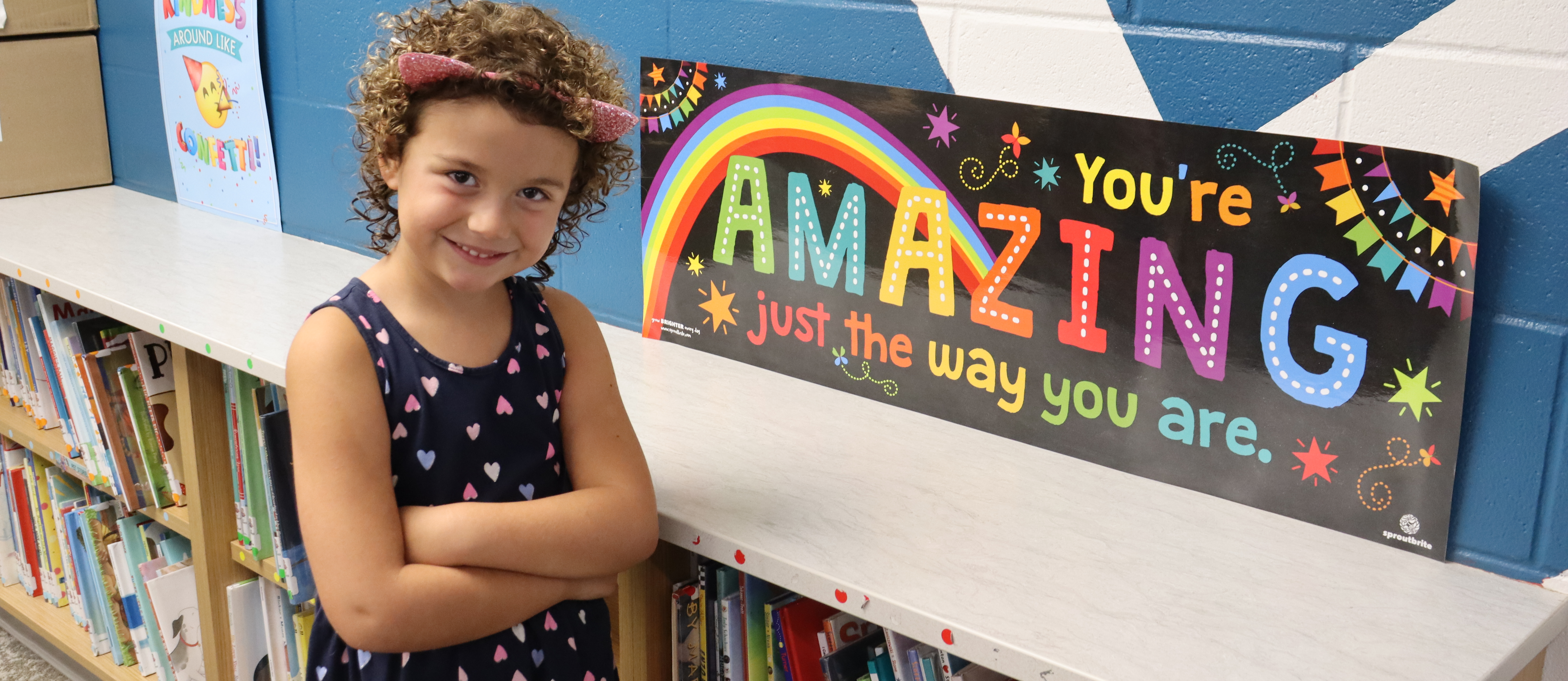 Student standing by sign that says you're amazing just the way you are.