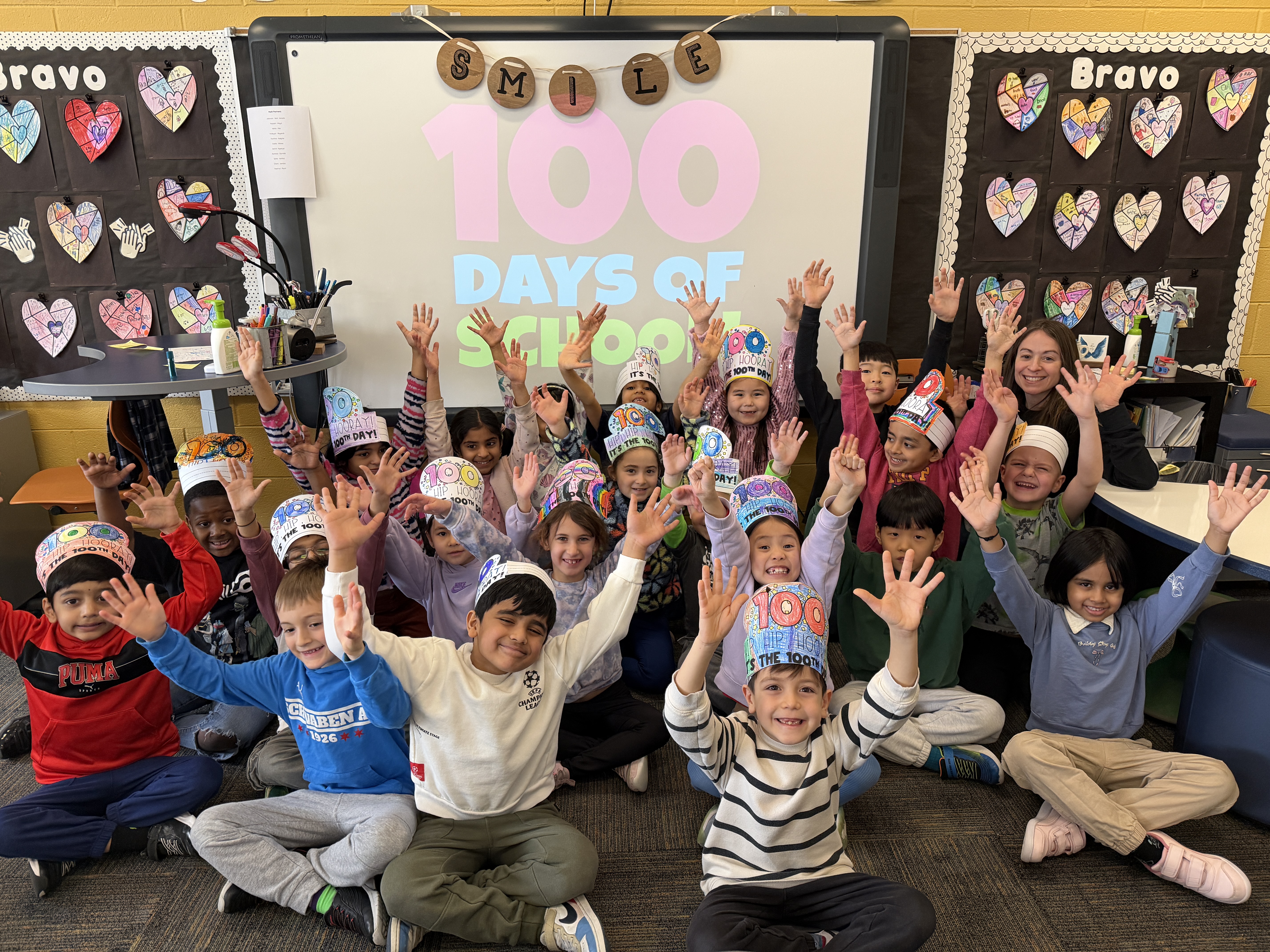 Students cheering with their arms up with 100 day hats on.