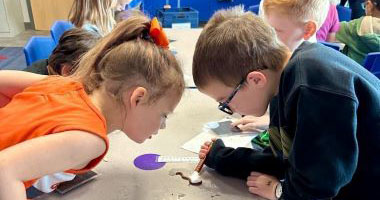 Young students examining a worm