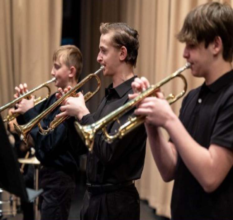 3 boys playing trumpets during a band concert