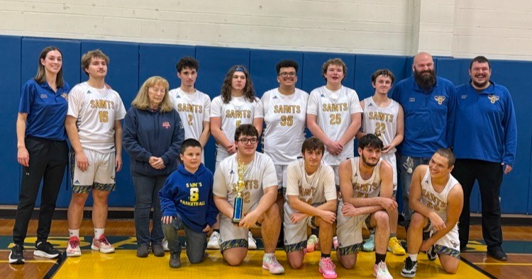 Boys basketball players and coaches holding tournament trophy