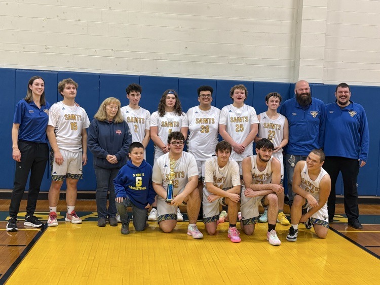 Boys varsity basketball players holding trophy