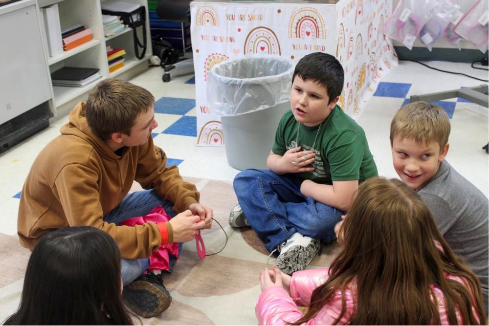 Tenth-grader Austin Lincoln, left, listens to elementary schoolers
