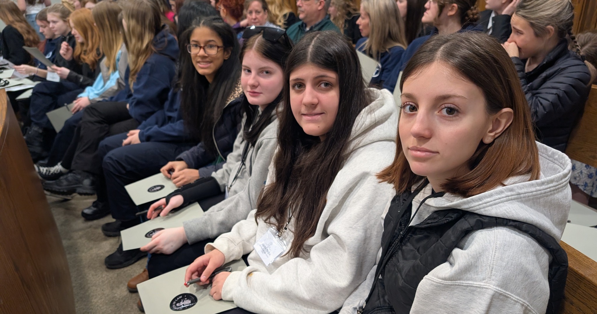 Four older female students sitting and holding folders