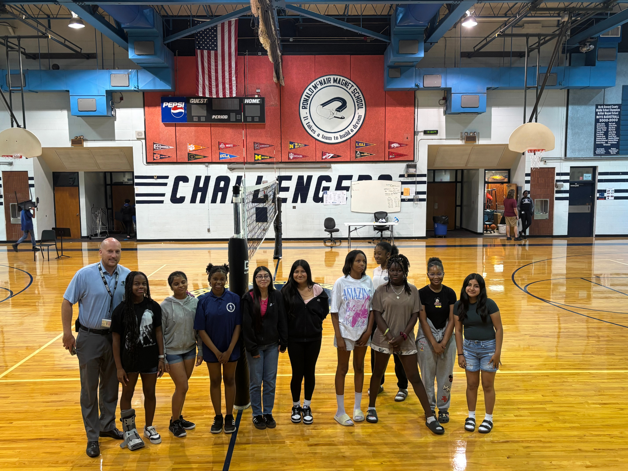 Principal Stewart and the girls volleyball team in the gym