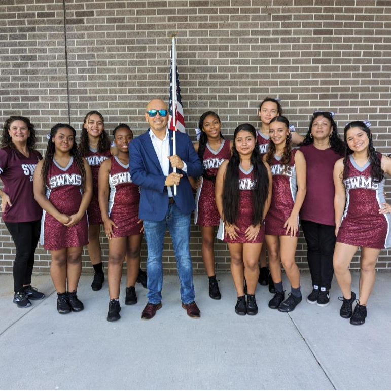 SWMS Dance Team with a local public official holding a flag before a local parade